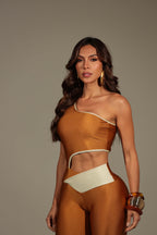 Modella indossa tuta intera monospalla bronzo metallizzato con tagli cut-out e bordo crema in vita.