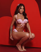 Donna in intimo rosa cipria con perle e volant, posa accovacciata, completo lingerie elegante e sensuale